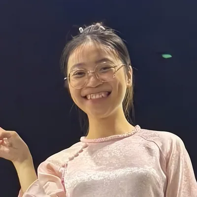 Eimee, Miss Saigon Tours guide, smiling in a pink ao dai at night